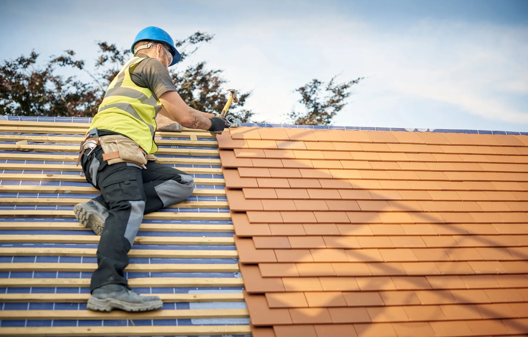 A restored terracotta tile roof on a Brisbane home under a clear blue sky